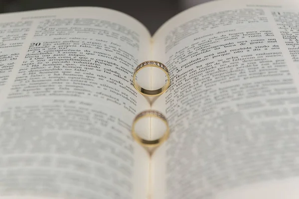 Anillos de boda en una sagrada Biblia "Bíblica Sagrada". Concepto de unión, amor, compañerismo, fidelidad. Unión religiosa. Enfoque selectivo . —  Fotos de Stock