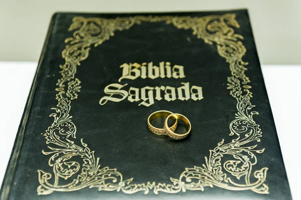Anillos de boda en una sagrada Biblia "Bíblica Sagrada". Concepto de unión, amor, compañerismo, fidelidad. Unión religiosa. Enfoque selectivo . —  Fotos de Stock