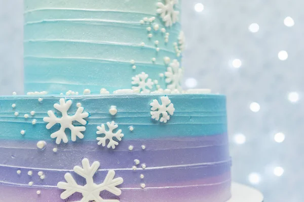 Zugeschnittene Fotokuchen zeigen Details wunderbarer blauer und lila Geburtstagstorten, die mit Schneeflocken dekoriert sind. zweistufige Torte auf blauem Hintergrund mit unfokussiertem Licht. Studioaufnahme mit selektivem Fokus — Stockfoto