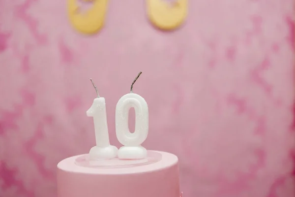 Birthday cake with candles as number ten on pink arabesques background. — Stock Photo, Image