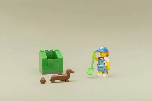 Frau mit Schaufel neben grünem Mülleimer auf der Suche nach ihrem Hundehaufen. — Stockfoto
