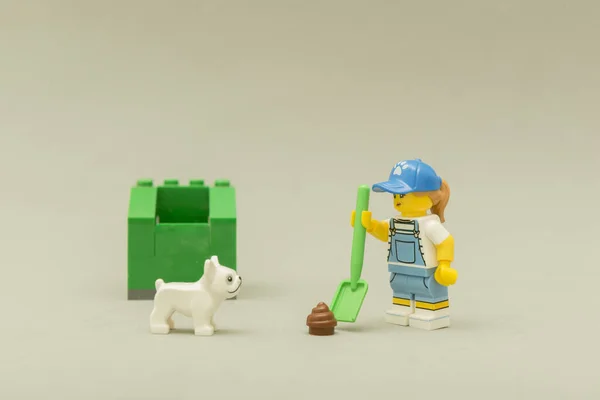 Woman holding a shovel next to a green trash bin looking for her dog poop. — Stockfoto