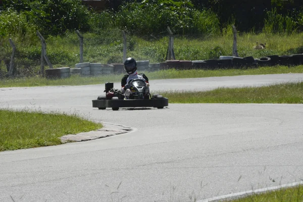 Side view of go-kart driver driving on race track on sunny day — 스톡 사진