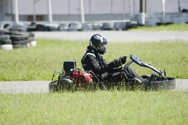 Oldalnézet go-kart vezető vezetés a versenypályán a napsütéses napon — Stock Fotó