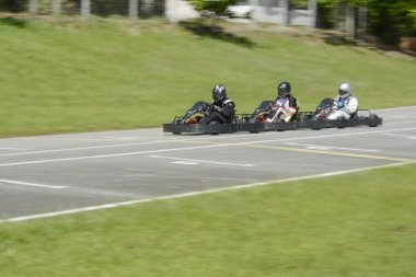 Üç rekabetçi, hızlı hareket eden go-kart 'ın dinamik görüntüsü