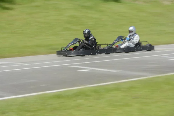 Vista lateral de imagen dinámica de dos competitivos, en movimiento rápido, go-karts . —  Fotos de Stock