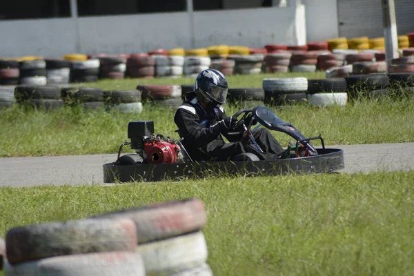 Oldalnézet go-kart vezető vezetés a versenypályán a napsütéses napon — Stock Fotó