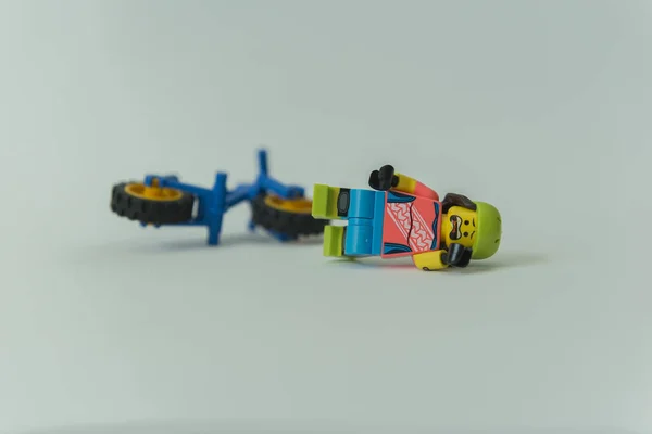 Biker minifigure lying on the floor after falling off his bicycle — Stock Photo, Image