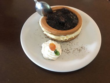 Lezzetli böğürtlenli peynirli keki çırpılmış krema ve kayısı ile ahşap bir masada beyaz seramik tabağın köşesinde kapat..