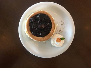 Lezzetli böğürtlenli peynirli keki çırpılmış krema ve kayısı ile ahşap bir masada beyaz seramik tabağın köşesinde kapat..