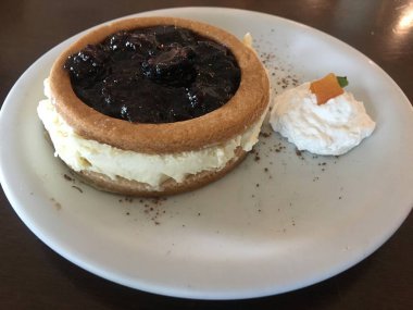 Lezzetli böğürtlenli peynirli keki çırpılmış krema ve kayısı ile ahşap bir masada beyaz seramik tabağın köşesinde kapat..