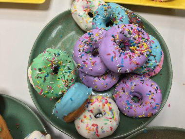 Lezzetli renkli çörekleri konfetiyle kapatın. Çikolatalı donutlar, pembe jöleli ve şekerli çörekler. Seçici odak.