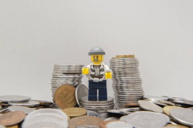 Florianopolis, Brezilya, 28 Mart 2020: Bir yığın madeni paranın yanında kelepçelenmiş haydut. Suç beyaz arka planda para getirmez. Banka soygunu. Lego minyatürleri Lego Grubu tarafından üretiliyor..