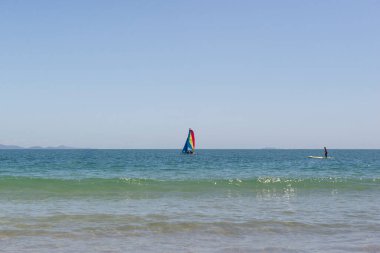 Mavi denizde küçük renkli katamaran yelkenlisi. Denizde renkli yelkenli katamaran yatı. Yatçılık. Brezilya, Florianopolis yakınlarında Atlantik okyanusunun turkuaz suları. Klasik Mavi Renk.