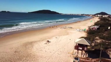 Florianopolis - Brezilya. 24 Mayıs 2020: Brezilya 'da tekir balıkçılığı sırasında sahilde yürüyen insanların hava görüntüsü. Tahta tekneler kıyıya demir atmış, bir balık sürüsünü bekliyorlar..