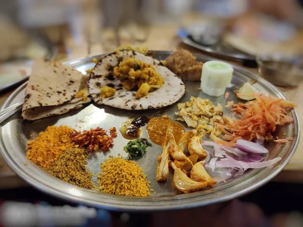Indian dish with various chatnis,fried garlic, cucumber,bhakri,chapati, pickle,onion slices, carrot,lemon, papad, green chutney — Stock Photo, Image