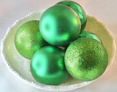 Beyaz karlı bir kasede yeşil toplar