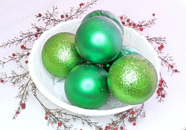 Karlı bir kasede yeşil toplar ve meyveler