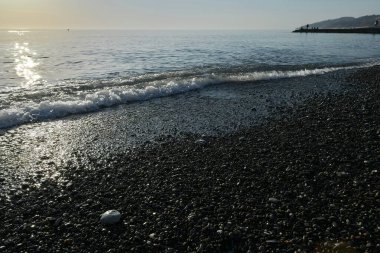 Deniz kıyısında gün batımında çakıl taşı plajı