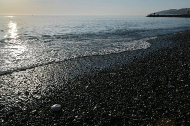 Deniz kıyısında gün batımında çakıl taşı plajı