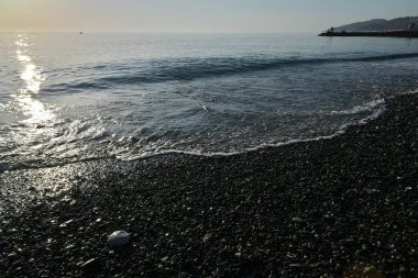 Deniz kıyısında gün batımında çakıl taşı plajı