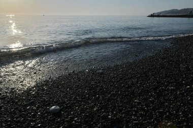 Deniz kıyısında gün batımında çakıl taşı plajı