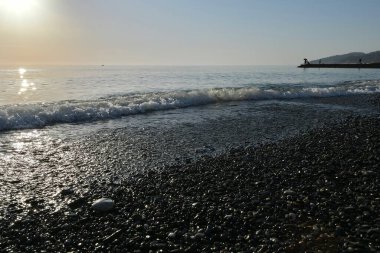 Deniz kıyısında gün batımında çakıl taşı plajı