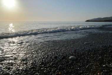 Deniz kıyısında gün batımında çakıl taşı plajı