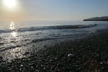 Deniz kıyısında gün batımında çakıl taşı plajı