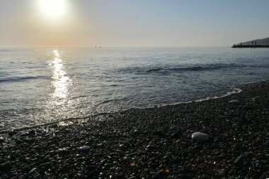 Deniz kıyısında gün batımında çakıl taşı plajı