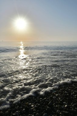 Deniz kıyısında gün batımında çakıl taşı plajı