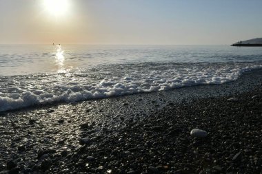 Deniz kıyısında gün batımında çakıl taşı plajı