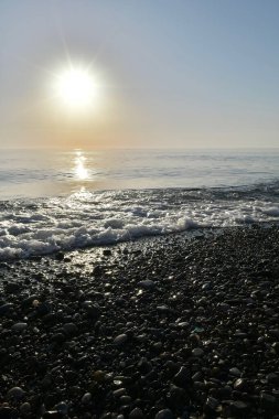 Deniz kıyısında gün batımında çakıl taşı plajı