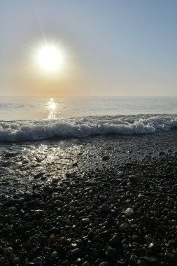 Deniz kıyısında gün batımında çakıl taşı plajı