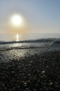 Deniz kıyısında gün batımında çakıl taşı plajı