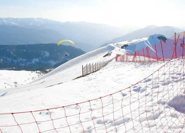 paragliding over a snowy mountain landscape at a ski resort