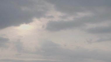Hızla hareket eden gri bulutların ötesini gören yükselen güneşin hızlandırılmış videosu