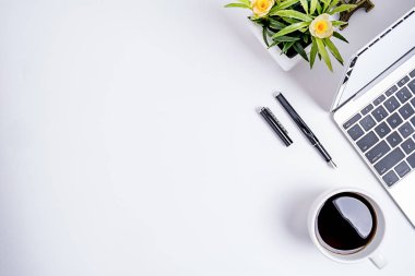 Ofis aksesuarları olan çalışma alanı ofis masaüstü. Defter, kalem, kahve ve çiçekli bir masa. Kopyalama alanı olan üst görünüm.