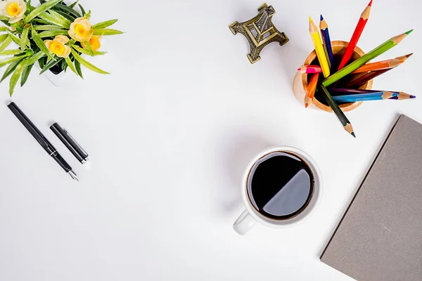 Workspace office desktop with office accessories. Desktop with notebook, pen, cup of coffee and flower. Top view with copy space.