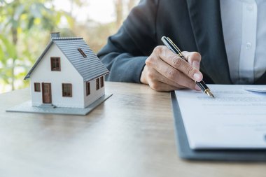 Emlakçı ve müşteri ev, sigorta ya da kredi sözleşmesi imzalıyor.