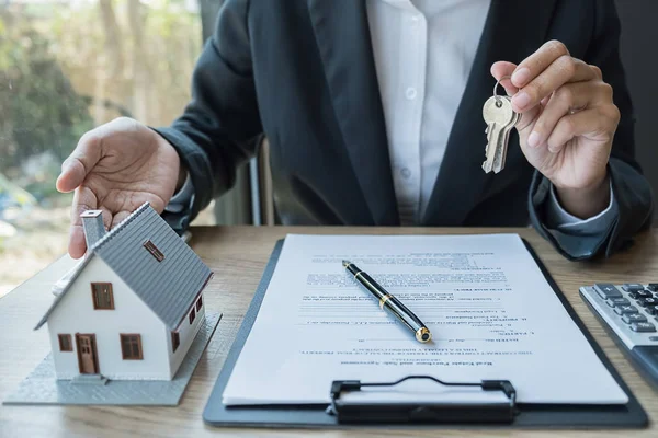 Agente de bienes raíces que tiene una llave y pidiendo al cliente un contrato para comprar, obtener un seguro o préstamo de bienes raíces o propiedades. — Foto de Stock