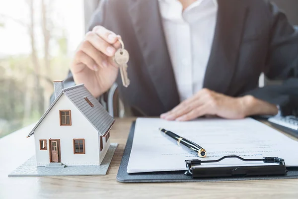 Agente de bienes raíces que tiene una llave y pidiendo al cliente un contrato para comprar, obtener un seguro o préstamo de bienes raíces o propiedades. — Foto de Stock