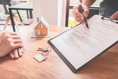 Emlakçı ve müşteriyle ev modeli satın alma, sigorta ya da kredi alma ya da emlak ya da mülkiyet sözleşmesi hakkında tartışıyor.