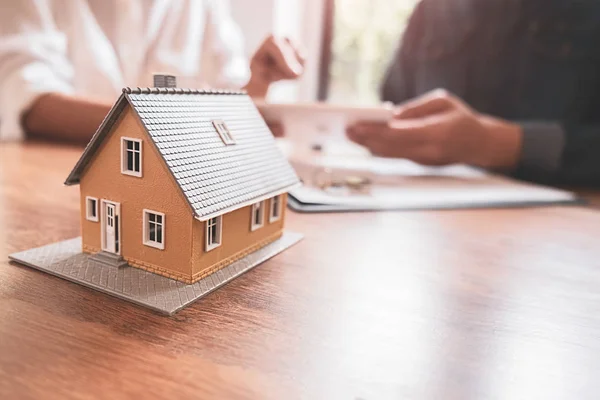 Modello di casa con agente e cliente discutere per il contratto di acquistare, ottenere l'assicurazione o prestito immobiliare o immobiliare. — Foto Stock