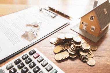 Ev modeli, anahtar, sözleşme belgesi ve hesap makinesi olan emlakçı masası satın alma, sigorta veya kredi alma veya emlak veya mülkiyet sözleşmesi için. 