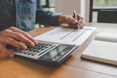 İş adamlarının iş verilerini hesaplamak için hesap makinesi kullanarak yakın plan çekimleri, merkez ofiste muhasebe belgesi.