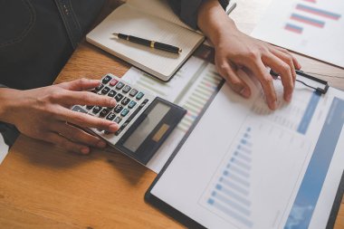 İş adamlarının iş verilerini hesaplamak için hesap makinesi kullanarak yakın plan çekimleri, merkez ofiste muhasebe belgesi.