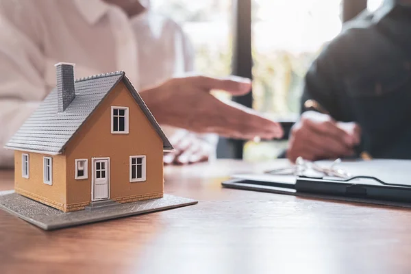 Modello di casa con agente e cliente discutere per il contratto di acquistare, ottenere l'assicurazione o prestito immobiliare o immobiliare. — Foto Stock