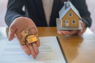 Emlakçının elinde anahtar var ve müşteriden satın almak, sigorta yaptırmak ya da emlak veya emlak almak için sözleşme istiyor..