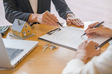 Emlakçı ve müşteriyle ev modeli satın alma, sigorta ya da kredi alma ya da emlak ya da mülkiyet sözleşmesi hakkında tartışıyor.